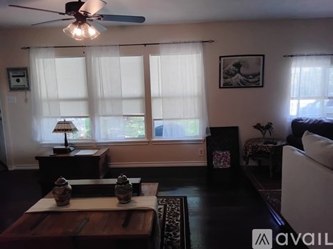A living room with a ceiling fan, a table with two vases, and a couch.
