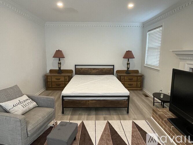 A bedroom with a bed, couch, and two lamps.