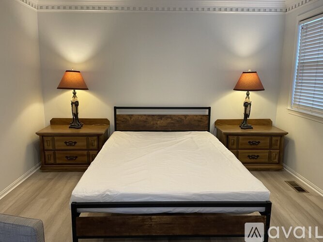 A bedroom with a bed, two nightstands with lamps, and a window.
