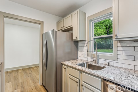 A kitchen with a stainless steel refrigerator and a window.