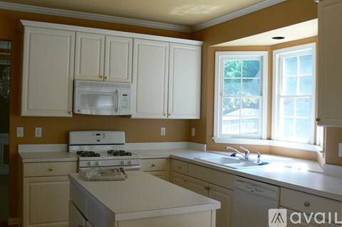 A kitchen with white cabinets and appliances.