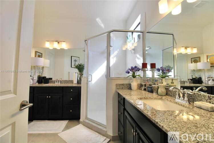 A bathroom with a sink, mirror, and a glass shower door.