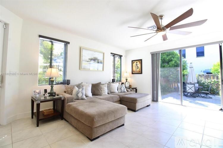 A living room with a couch, a coffee table, and a ceiling fan.