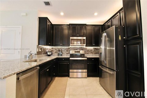 A modern kitchen with black cabinets and stainless steel appliances.