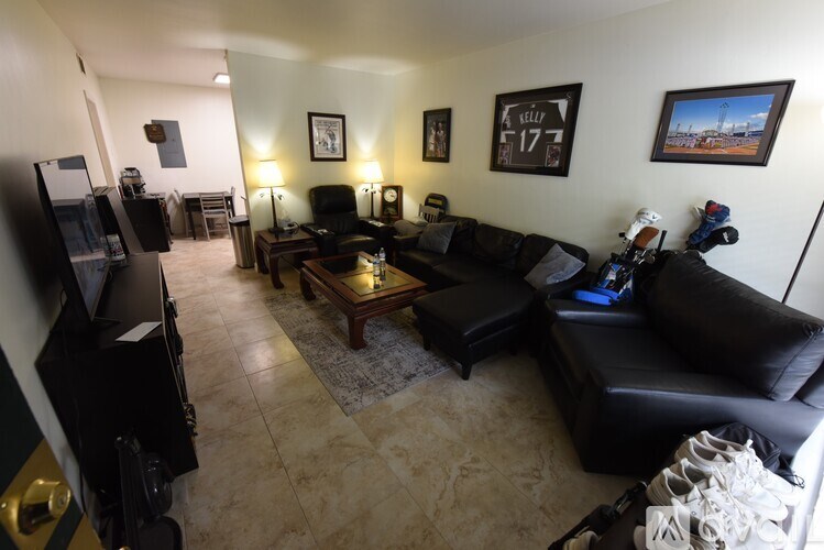 A living room with a black couch, a coffee table, and a television.