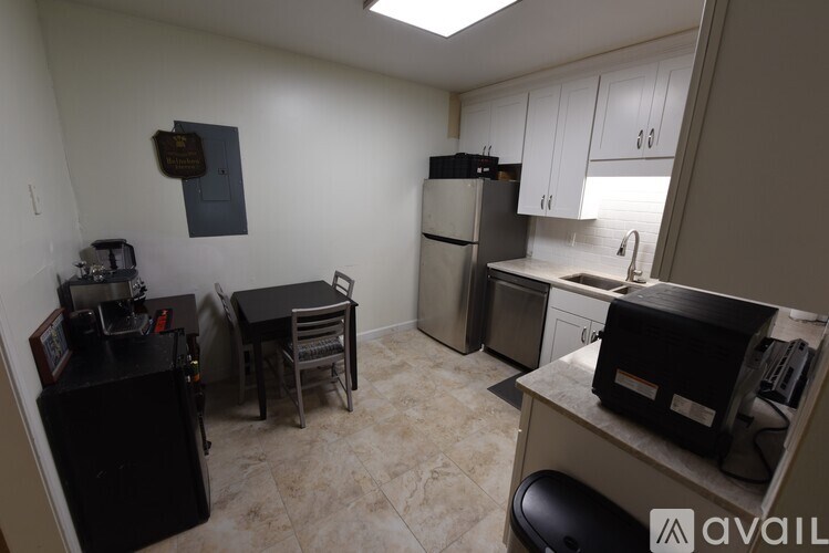 A kitchen with a refrigerator, sink, and cabinets.