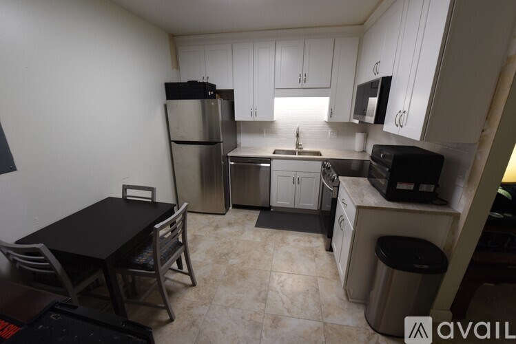 A kitchen with a table and chairs in the foreground and a refrigerator, microwave, and oven in the background.