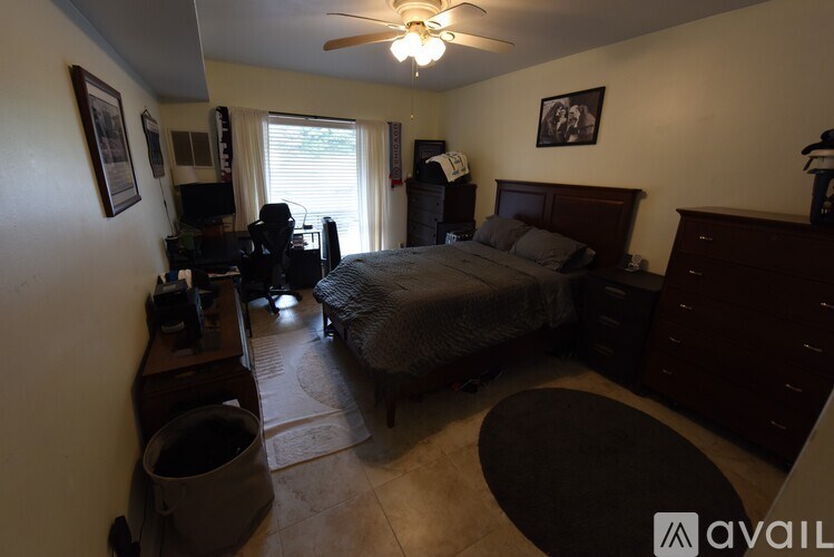 A bedroom with a bed, dresser, and ceiling fan.