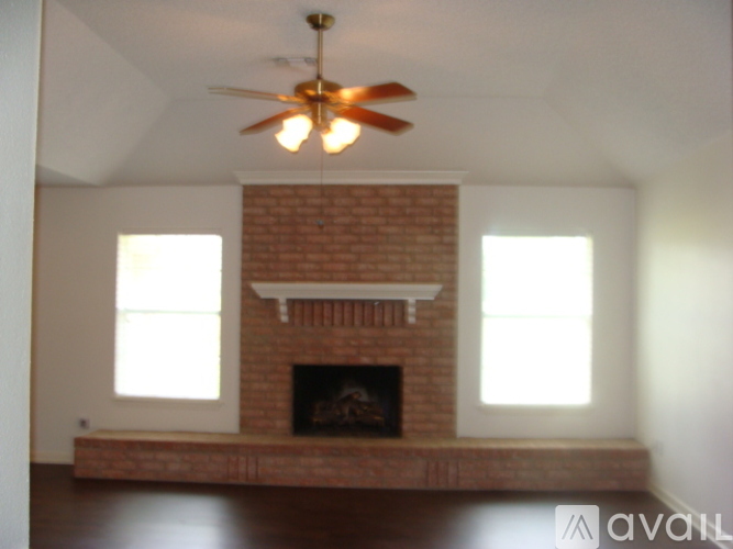 A living room with a brick fireplace and a ceiling fan.