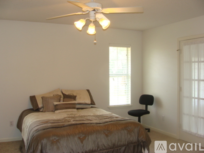 A bedroom with a bed, chair, and window.