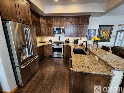 A kitchen with dark wood cabinets and a granite countertop.