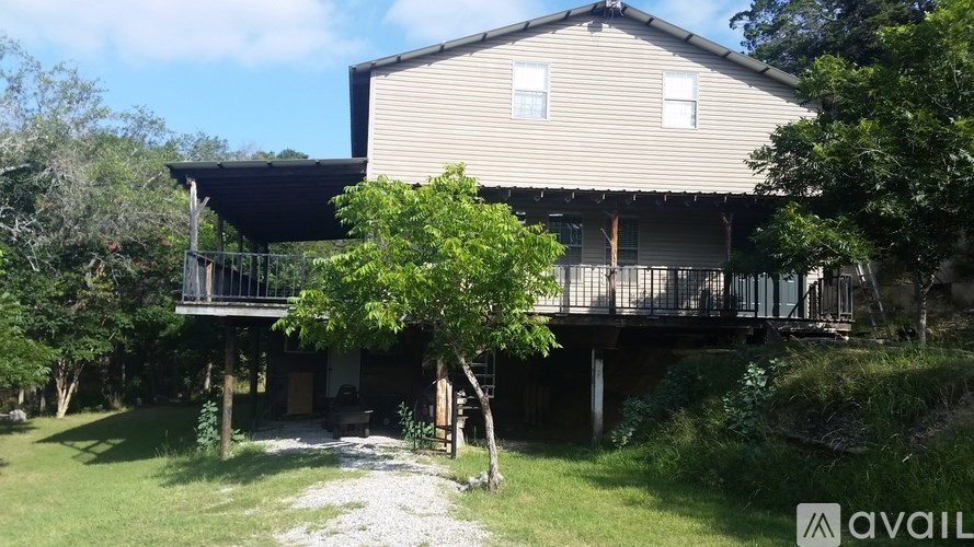 A house with a balcony and a tree in front of it.