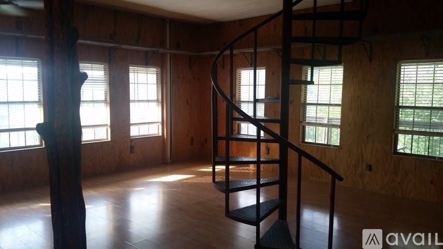 A spiral staircase in a room with wooden walls and windows.