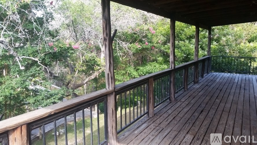 A wooden deck with a railing and trees in the background.