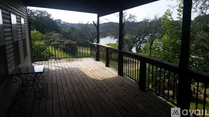 A wooden deck with a metal railing overlooks a lake and trees.