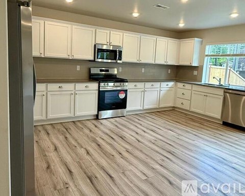 A kitchen with white cabinets and a wooden floor.