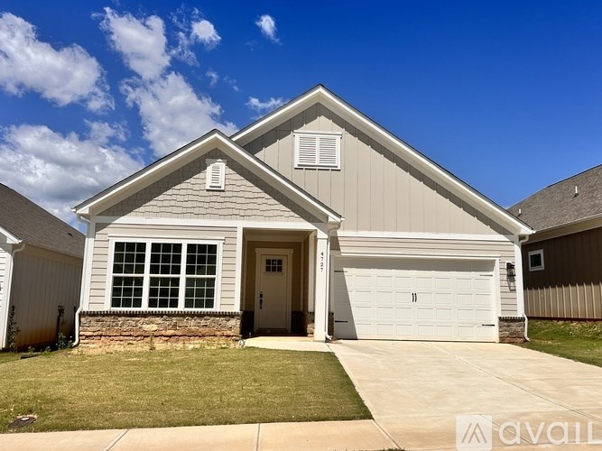A two-story house with a garage and a stone wall.
