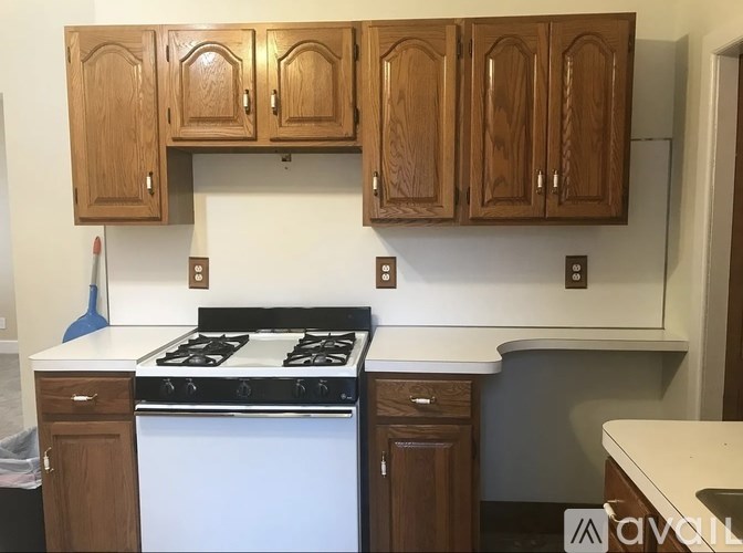 A kitchen with a white stove and wooden cabinets.