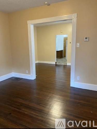 A room with wooden floors and a white doorway leading to another room.