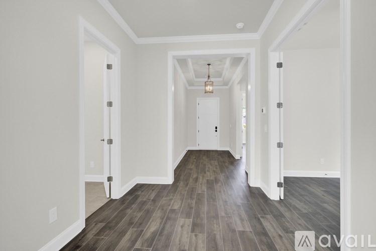 A hallway with wood flooring and white walls.