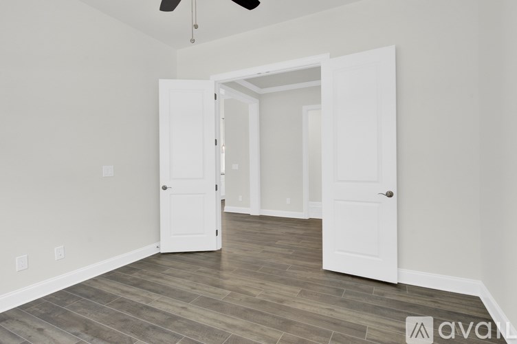 A room with a white door and a ceiling fan.