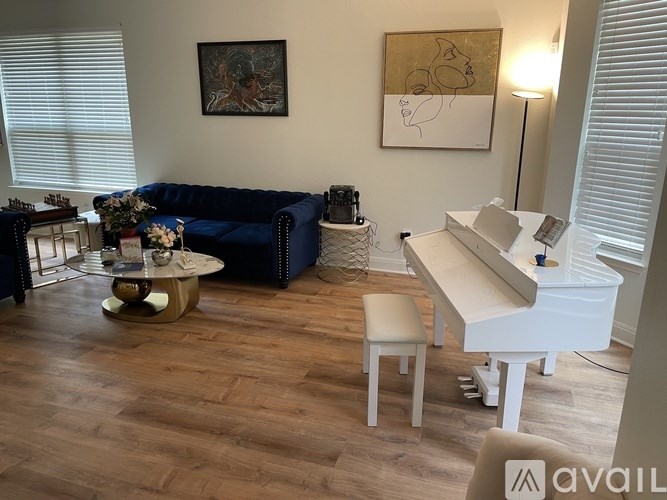 A living room with a blue couch, a white piano, and a coffee table.