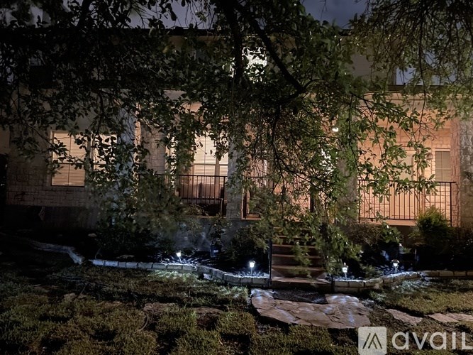 A nighttime view of a building with trees and bushes in the foreground.