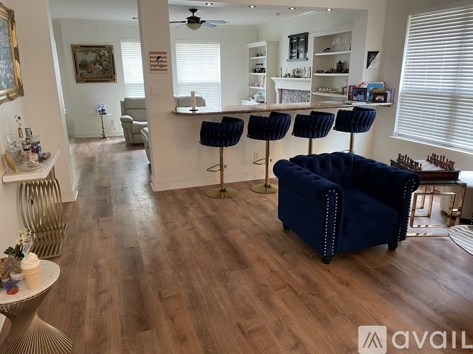 A living room with a blue chair and a bar area.