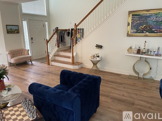 A living room with a blue velvet sofa and a chess board on the coffee table.