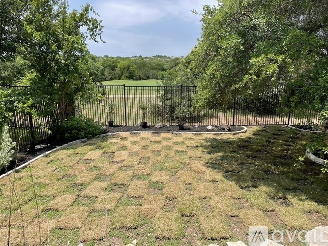 A backyard with a fence and a lawn.