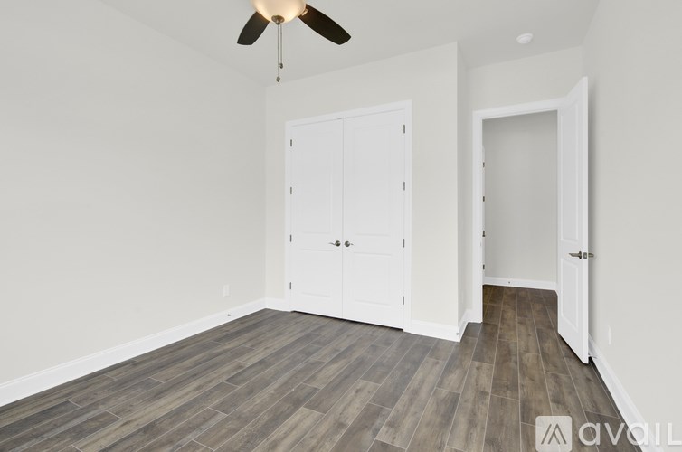 A room with a ceiling fan and a wooden floor.