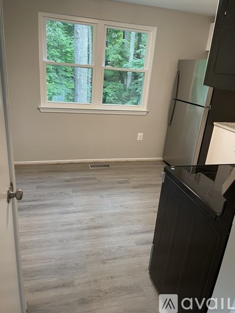 A kitchen with a refrigerator and a window with a view of trees.