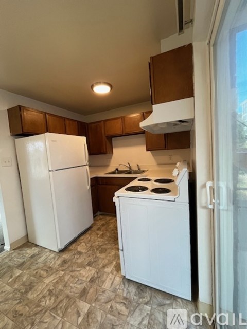 A kitchen with white appliances and brown cabinets.