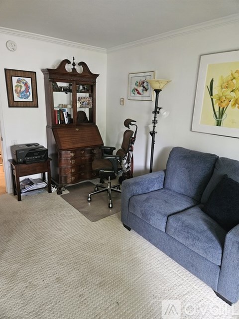 A living room with a blue couch and a wooden bookcase.
