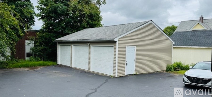 A detached garage with a car parked in front.