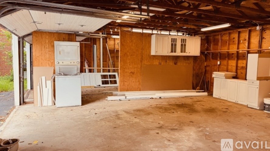 A room under construction with wooden walls and ceiling, and a white refrigerator in the corner.