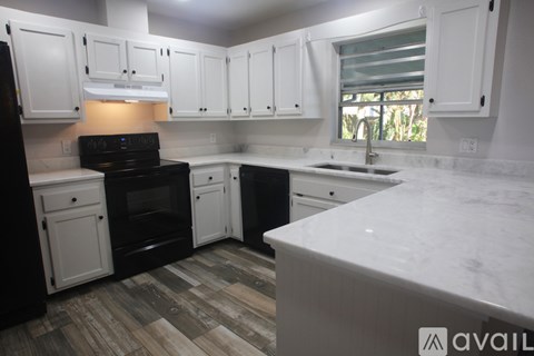 A kitchen with black appliances and white cabinets.