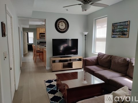 A living room with a brown couch and a television on a stand.