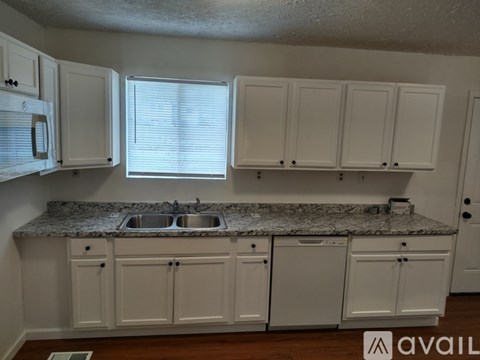 A kitchen with granite countertops and white cabinets.