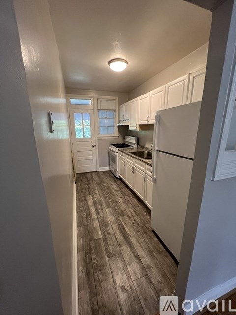 A kitchen with white cabinets and a wooden floor.