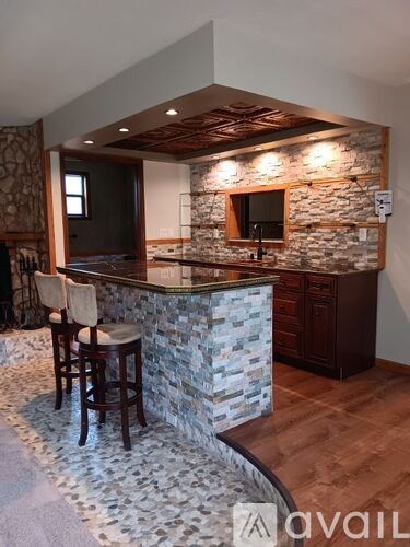 A kitchen with a stone bar counter and wooden chairs.