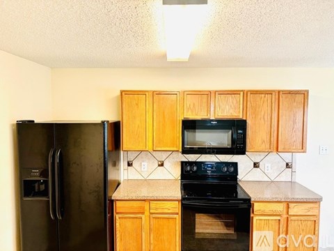 A kitchen with wooden cabinets and black appliances.