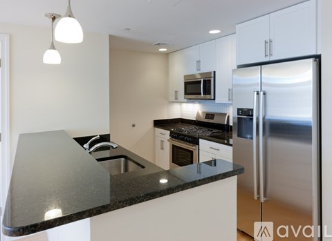 A kitchen with a black countertop and stainless steel appliances.