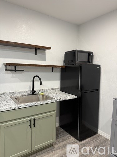A kitchen with a black fridge and a sink.