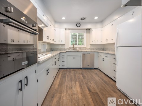 A modern kitchen with white cabinets and a wooden floor.