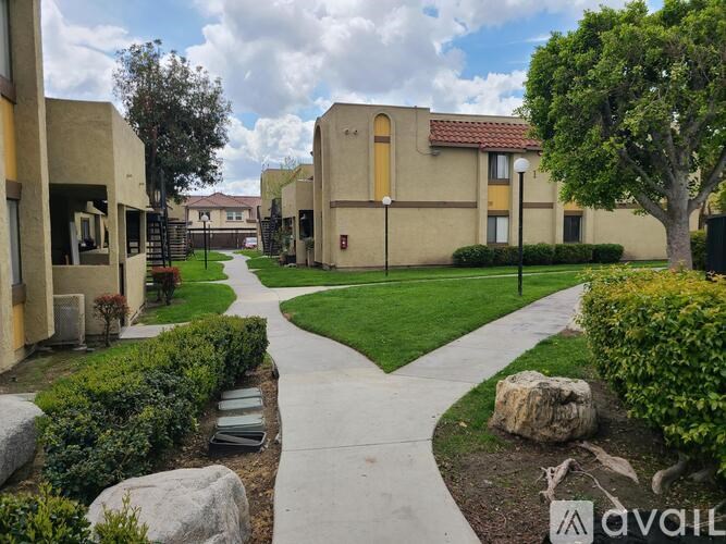 A pathway leads through a landscaped area in front of apartment buildings.