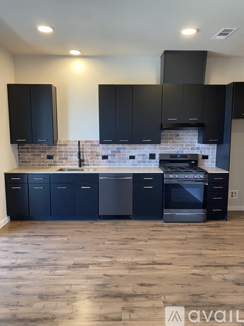 A kitchen with black cabinets and a brick backsplash.