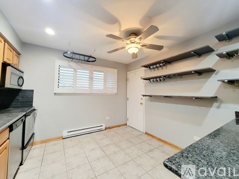 A kitchen with a fan, a stove, and a counter.