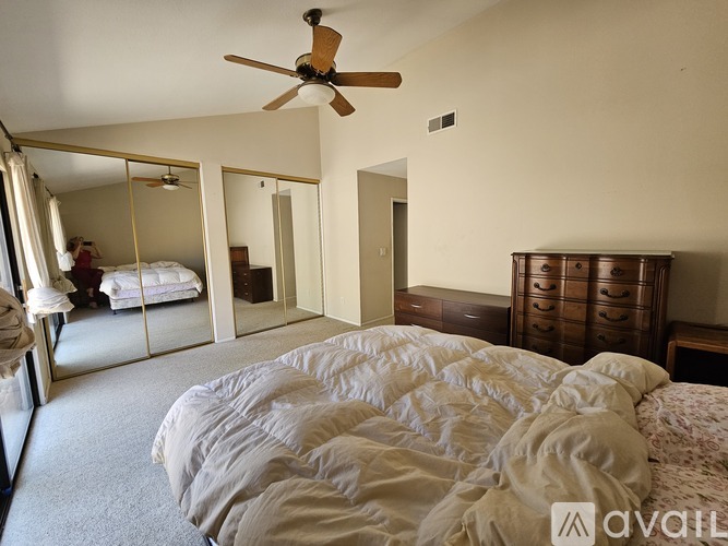 A bedroom with a large bed and a ceiling fan.