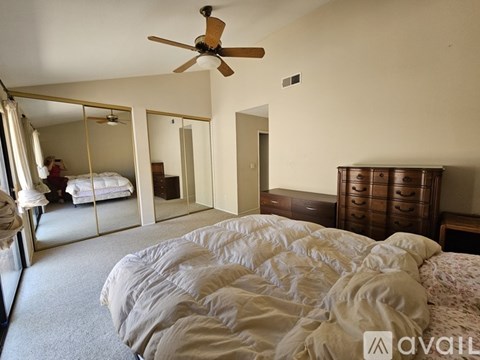 A bedroom with a large bed and a ceiling fan.